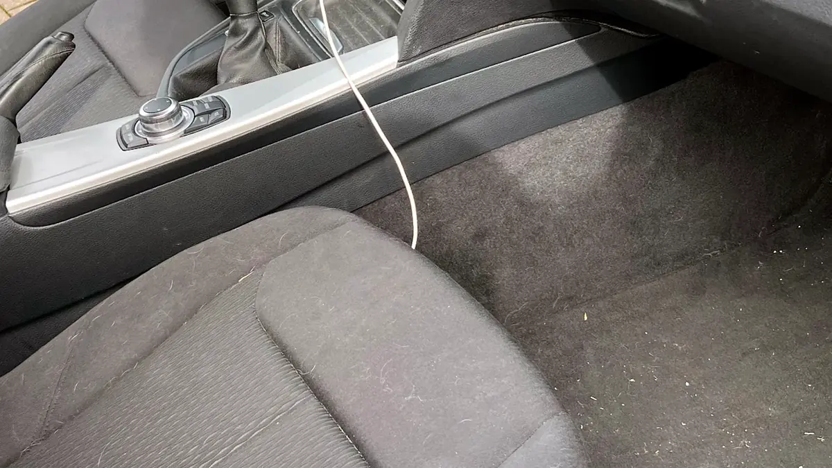 Intérieur de BMW avant nettoyage : moquettes poussiéreuses et débris